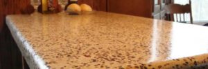 Polished terrazzo countertop with two wine bottles, two glasses, and two bread rolls in a kitchen setting.