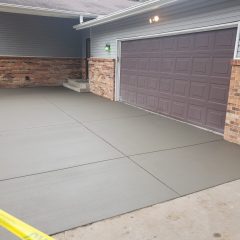 Freshly poured concrete driveway in front of a two-car garage, with caution tape blocking access.
