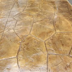 Stamped and stained concrete patio with irregular stone pattern in shades of tan and brown.