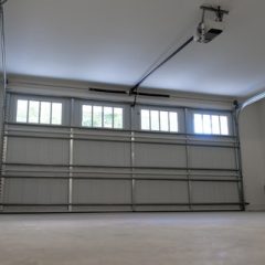 Empty garage interior with a closed sectional garage door and an automatic door opener mounted on the ceiling.